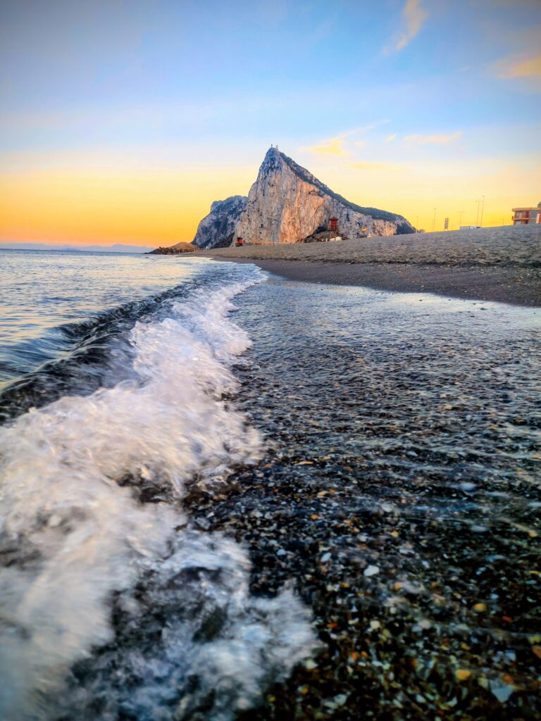 el peñon de Gibraltar al fondo sobre las olas de la playa en la línea de la concepción